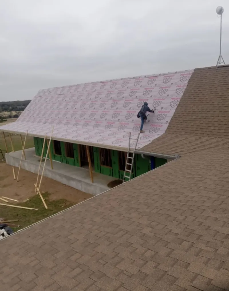 Worker preparing underlayment for a metal roof installation in Paragould